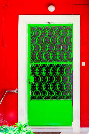green carved door with a pattern of green on a red wall backgroundの写真素材