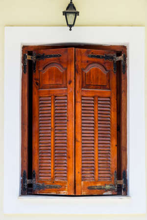 Old mediterranean red window shutters and building backgroundの写真素材