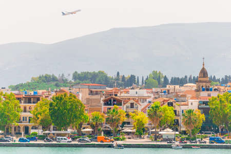 The plane flies over the roof of a residential building against the sky.の写真素材