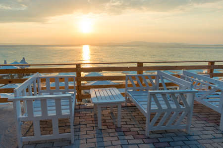 Range of wooden table and white chair for relaxation at restaurant near sea