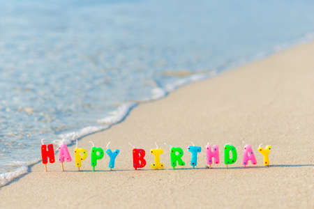 Happy birthday colorful candles on a beachの写真素材