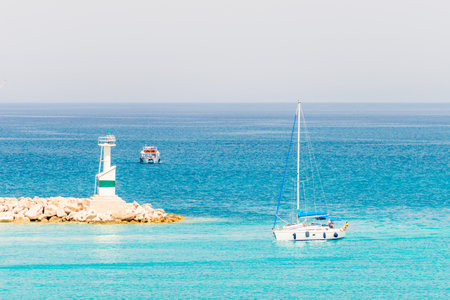 Lighthouse on ocean coastline over sky and shipの写真素材