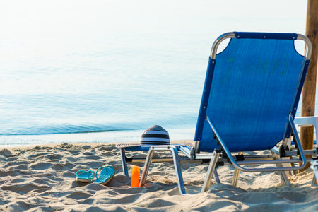 The stried hat lies on the edge of the chaise longue, the seashore with a beautiful view.の写真素材