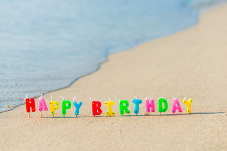 Happy birthday colorful candles on a beachの写真素材