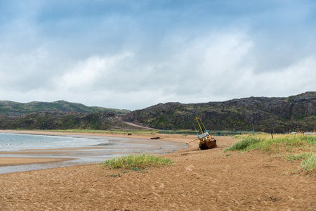 A fishing boat with a hole washed up on an empty beach of the North Seaの写真素材
