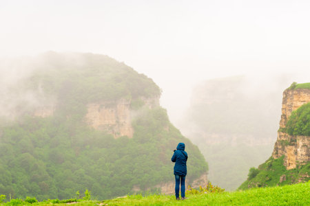 A man admires the beautiful view of the misty canyon in bad weather. The mountains of the North...