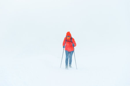 A young tourist girl climbs the snowy mountainside in a blizzard. Elbrus. Caucasusの写真素材