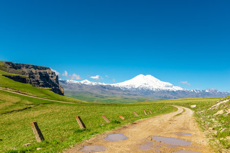 A dirt road on the plateau going to the Kanzhol plateau with a view of the Elbrus volcano. Russiaの写真素材