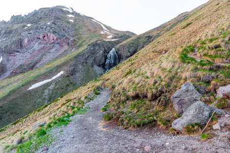 A mountain trail going down a steep slope to a picturesque waterfall. The North Caucasus. Russiaの写真素材