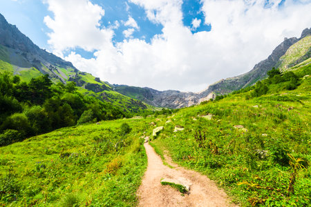 Beautiful highland landscape with a dirt road on a green mountain slope. Caucasus, Elbrus region.の写真素材