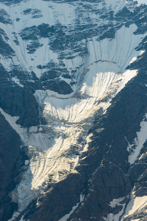 A stark view of a massive glacier sliding down a rocky mountainside. Caucasus Mountainsの写真素材