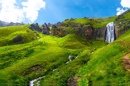 Picturesque landscape with beautiful Terskol waterfall and green slopes. Caucasus, Elbrus region.の写真素材