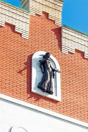 Decorative element in the form of a figure of a girl artist on the wall of a red brick houseの写真素材