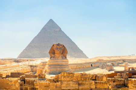 majestic Egyptian sphinx against the backdrop of ancient pyramids under the scorching sun of the Sahara desert. Cairoの写真素材