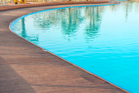 Wooden deck floor by the pool with clear azure waterの写真素材