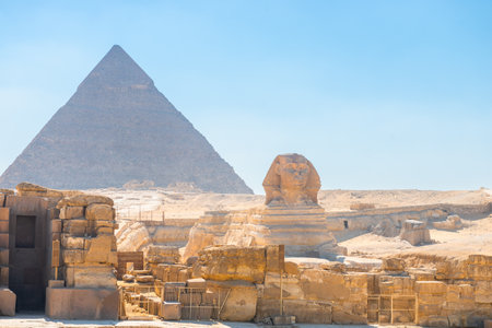 majestic Egyptian sphinx against the backdrop of ancient pyramids under the scorching sun of the Sahara desert. Cairoの写真素材