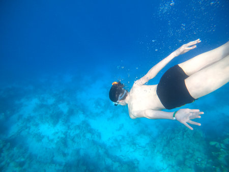 Boy snorkeling dive deep into the blue sea near the coral reef. Red Seaの写真素材