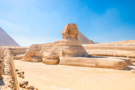 majestic Egyptian sphinx against the backdrop of ancient pyramids under the scorching sun of the Sahara desert. Cairoの写真素材