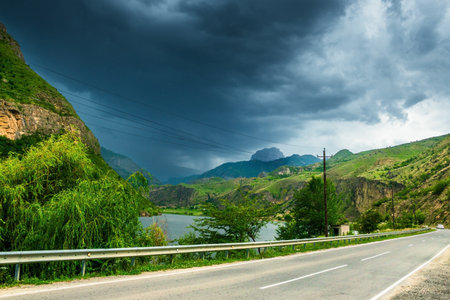 Dramatic mountain landscape with road near mountain lake in stormy weather. North Caucasus