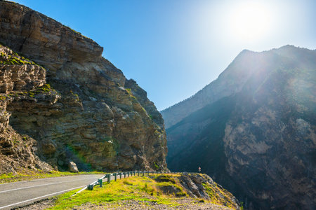 Landscape with a turn of a mountain road on a rocky ledge with a steep cliff into a deep abyss in the mountains of the North Caucasusの写真素材