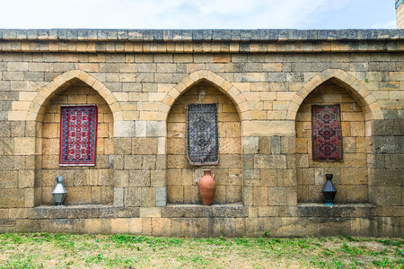 The inner side of the old fortress wall of the Naryn Kala citadel decorated with carpets and jugs....