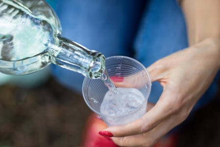 girl pour beverage from bottle into glass in outdoorの写真素材