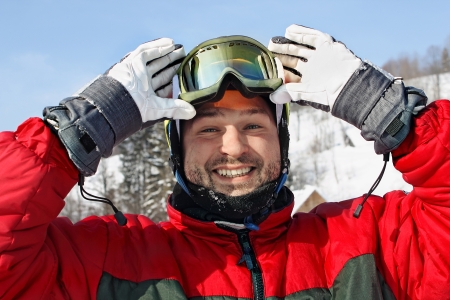 happy young man  lifting goggles  in winter mountians  の写真素材