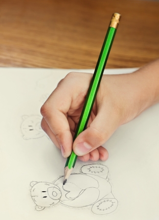 Child drawing teddy bears and heart with grey pencilの写真素材