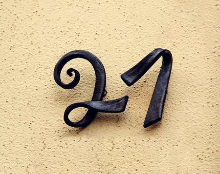 Metal house number twenty-one  Separate black lettering on a wall  の写真素材