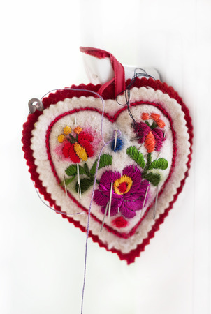 Embroidered pincushion in form heart with needles, handmadeの写真素材