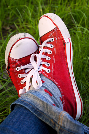 Feet in dirty red sneakers outdoors. Relax in summertime.のeditorial素材