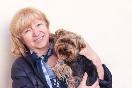Portrait of beautiful happy, smiling eldery woman hugging her little yorkshire terrier dog outdoors.の写真素材