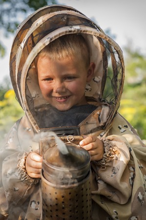 Young farm beekeeper boy using a smoker on bee yardの写真素材