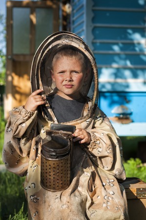Young farm beekeeper boy using a smoker on bee yardの写真素材