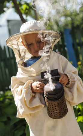 Young farm beekeeper boy using a smoker on bee yardの写真素材