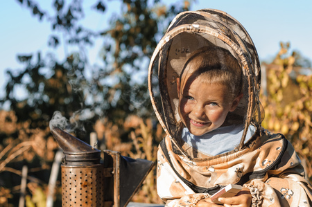 Little boy beekeeper blows smoker for bees.の写真素材