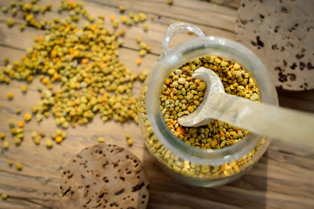 Grains of bee pollen in jar and wooden spoon on wooden table. Apitherapy. Bee products.の写真素材