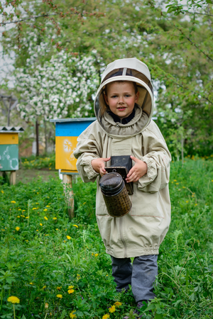 The boy in protective clothing beekeeper works on an apiary. Apiculture.の写真素材