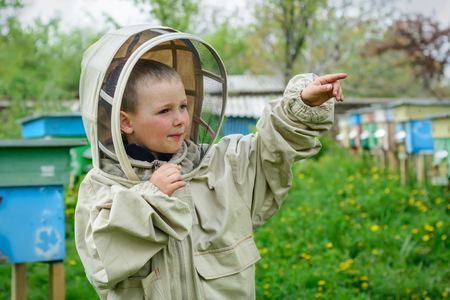 The boy in protective clothing beekeeper works on an apiary. Apiculture.の写真素材