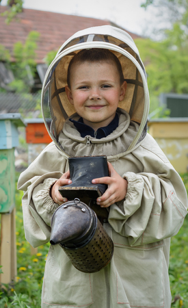 The boy in protective clothing beekeeper works on an apiary. Apicultureの写真素材