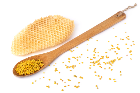 Bee pollen in a wooden spoon and a honeycomb on white background. Beekeeping products. Apitherapy.の写真素材