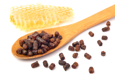 Granules of bee bread in a wooden spoon and a honeycomb are isolated on a white background. Apitherapy. Beekeeping products. Strengthening immunity.の写真素材