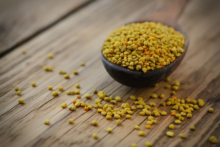 Bee pollen in spoon over wooden background. Healthy organic raw diet vegetarian food ingredient - bee pollen. Beekeeping products. Apitherapyの写真素材