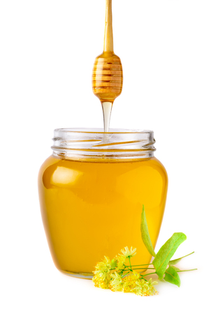 Glass jar of fresh linden honey with flowers of linden on white.の写真素材