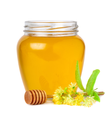 Glass jar of fresh linden honey with flowers of linden on white.の写真素材