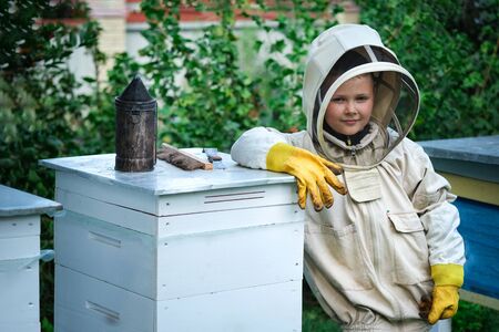 Boy beekeeper in apiary near beehives.Honeycomb with honey. Organic food concept. The most useful organic honey.の写真素材
