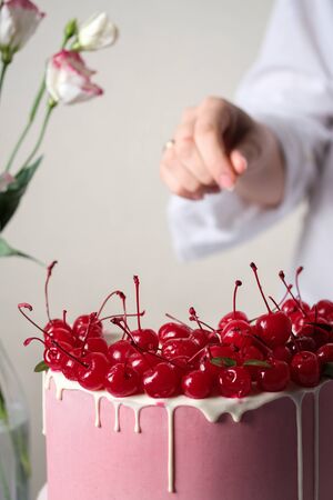 Cake with cherry. The confectioner decorates the cake.の写真素材