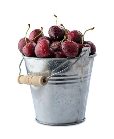 Ripe cherry in small metal bucket on white background.の写真素材