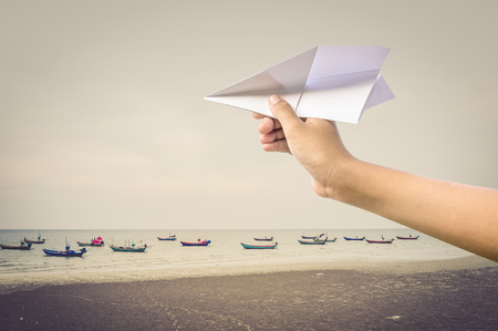 plane paper in children hand over sea and boats, vintage styleの写真素材