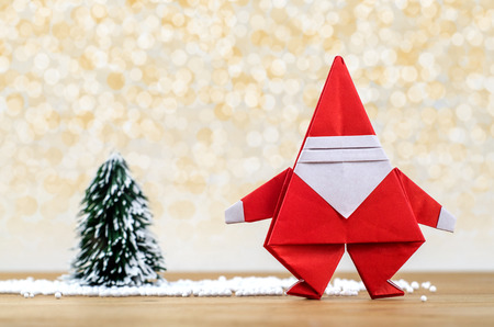 Santa Claus paper craft and christmas tree with lights snow winter background. Paper origami.の写真素材